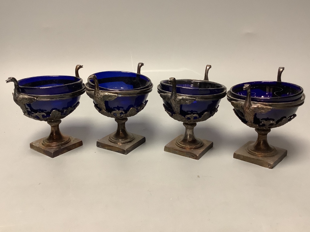 A set of four 19th century French pierced white metal circular pedestal salts with swan neck handles and later? blue glass liners